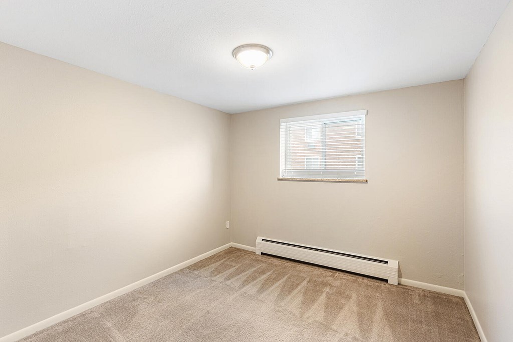 A room with a window and a radiator on the floor.