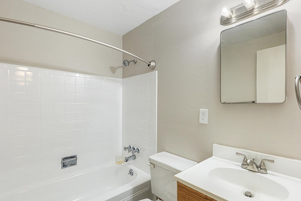 A white bathroom with a tub, sink, and mirror.