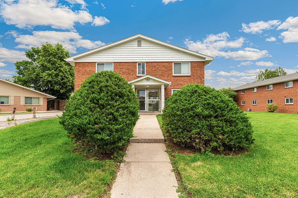 A house with a brick facade and a green lawn in front.