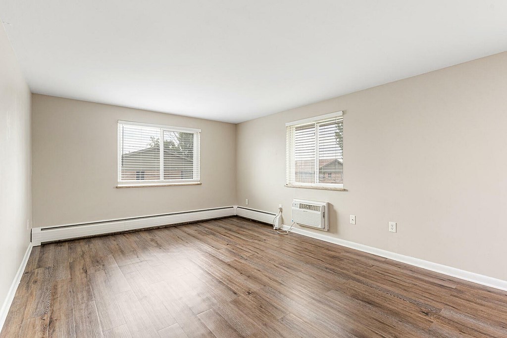 A room with wooden floors and two windows.