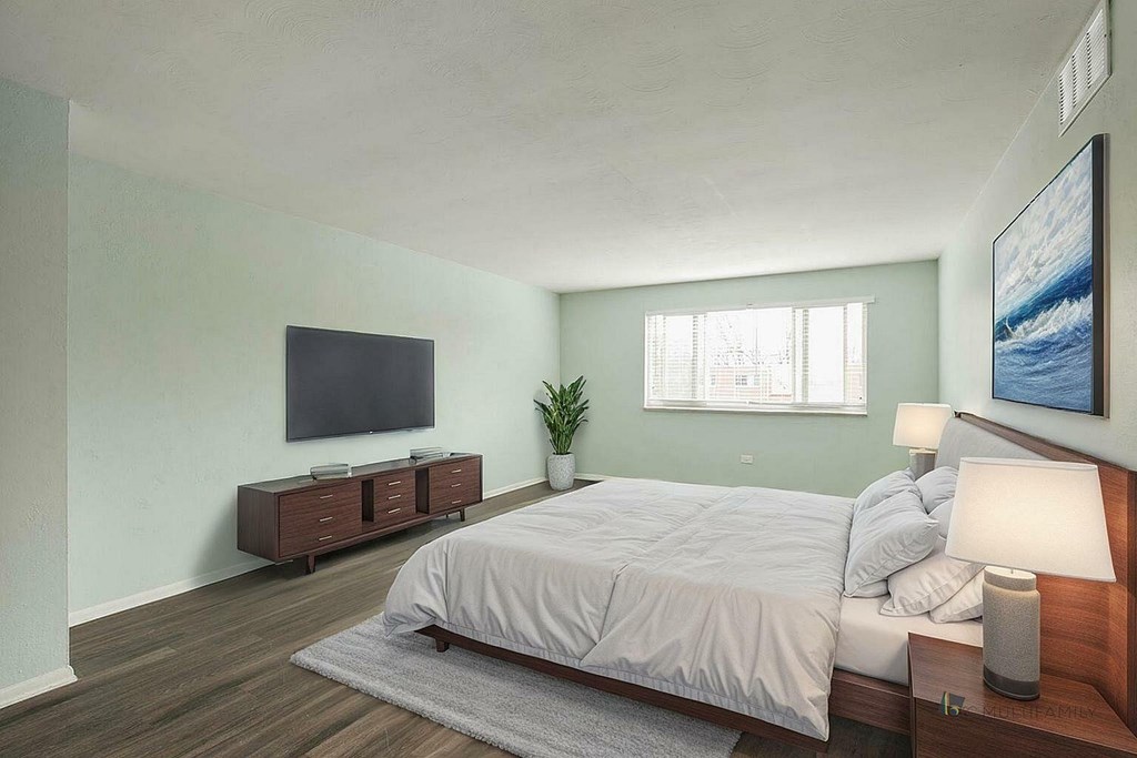 A bedroom with a bed, nightstand, and a plant.