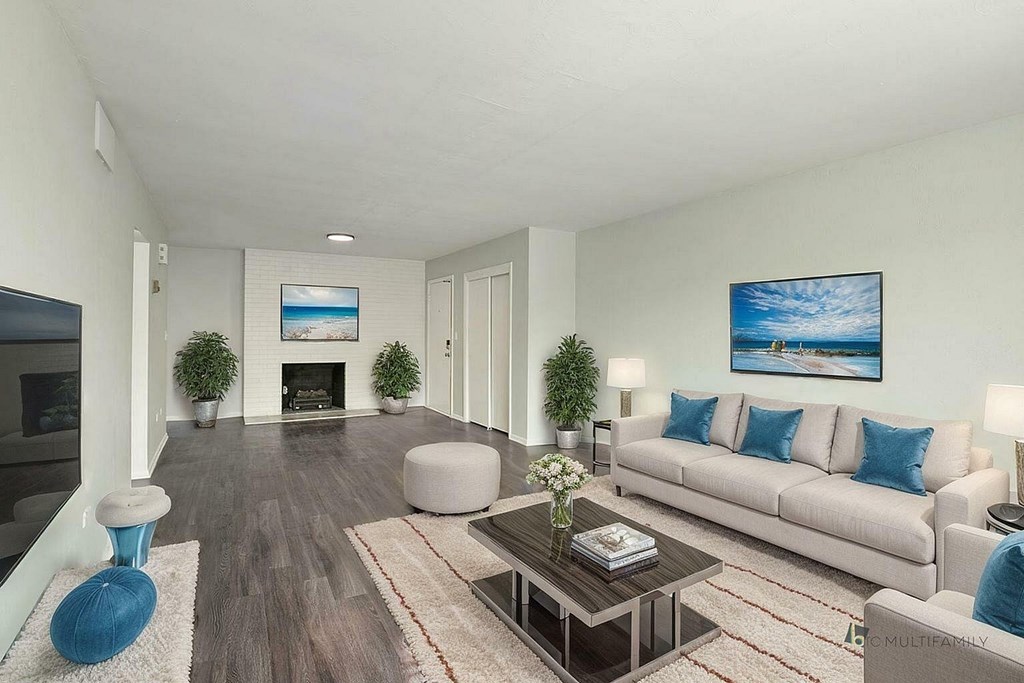 A living room with a white couch, a coffee table, and a painting on the wall.