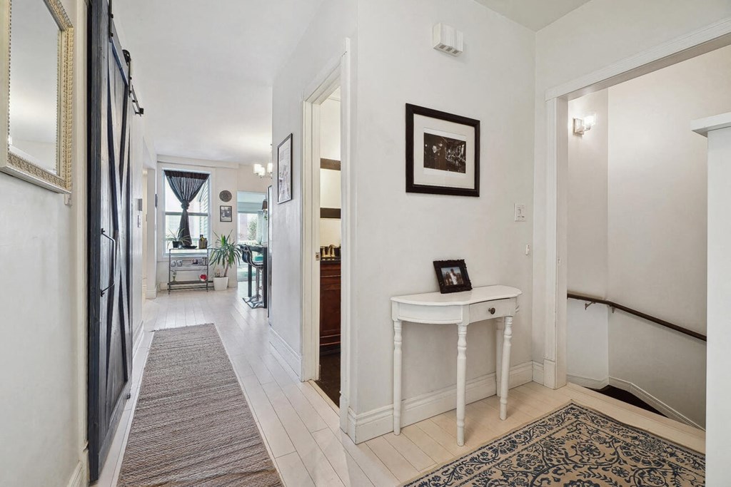 A hallway with a table and a framed picture on the wall.