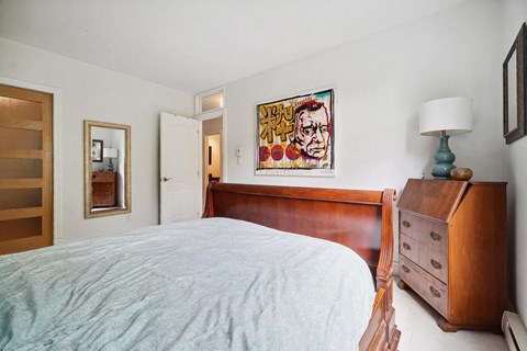 A bedroom with a bed, dresser, and a painting on the wall.