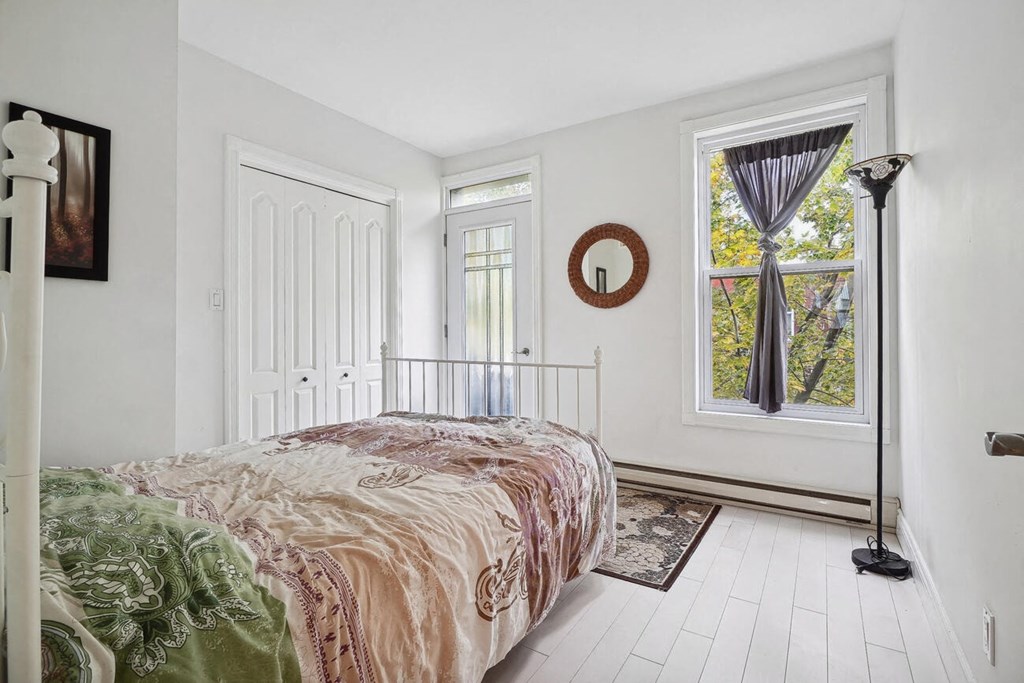 A bedroom with a bed, window, and a rug.