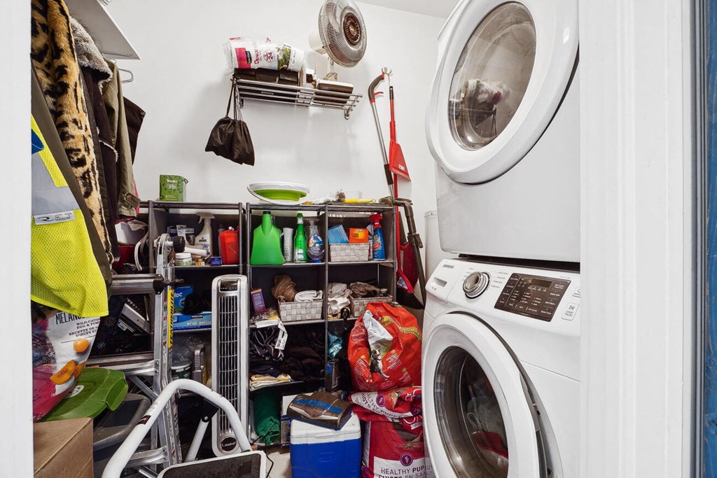 A small laundry room with a washer and dryer, and a shelf with various items on it.