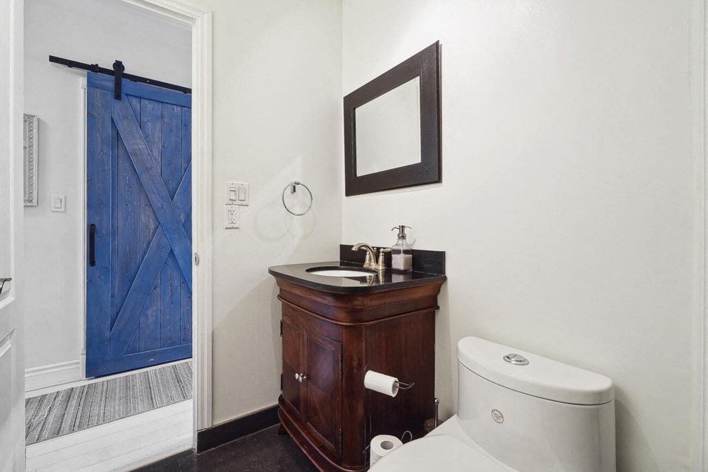 A bathroom with a toilet, sink, and mirror.