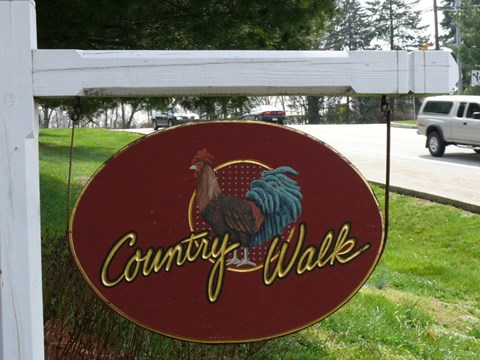 A sign that says "Country Walk" with a picture of a rooster on it.