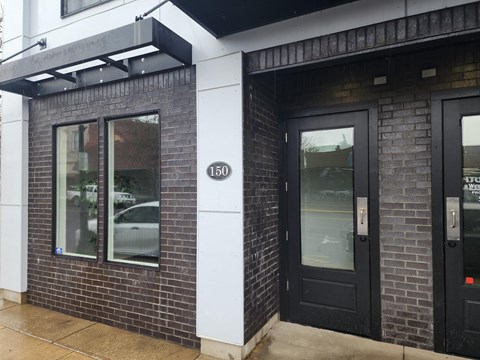 A building with a black door and a window with a reflection of a car.
