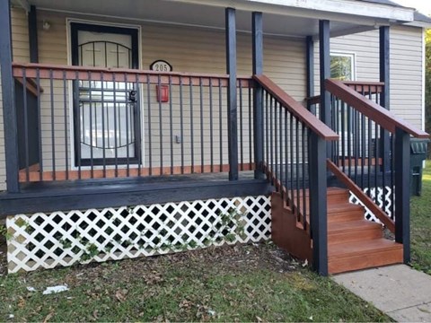 A house numbered 205 has a black railing on its porch.