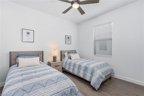 A bedroom with two beds and a ceiling fan.