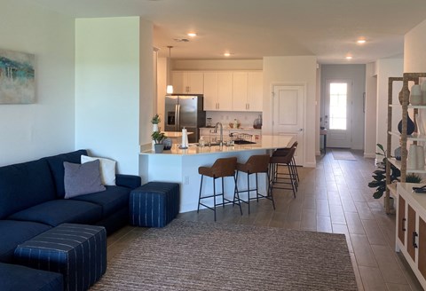 A living room with a blue couch and a kitchen in the background.