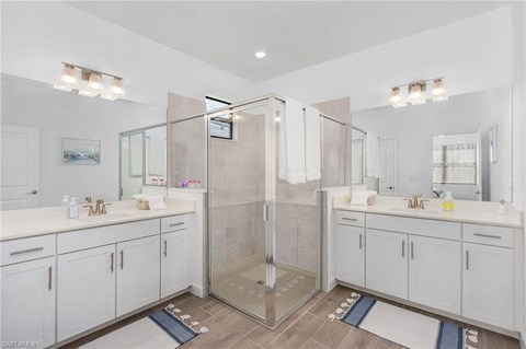 A bathroom with a walk-in shower and double sinks.