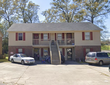A two-story house with a red and white exterior and a balcony on the second floor.