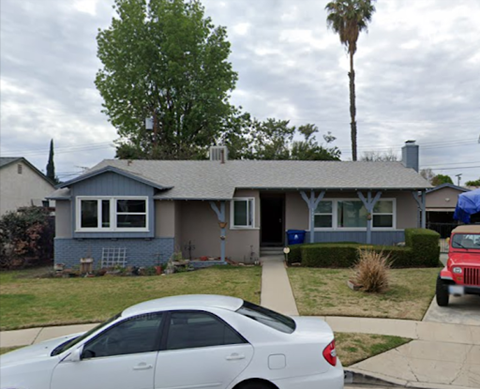 A silver car is parked in front of a house.