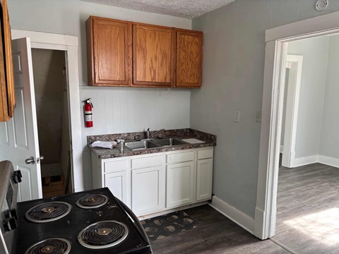 A kitchen with a black stove top oven and wooden cabinets.