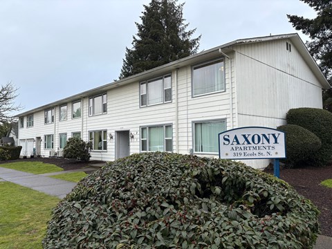 A white building with a sign that says Saxony Apartments.
