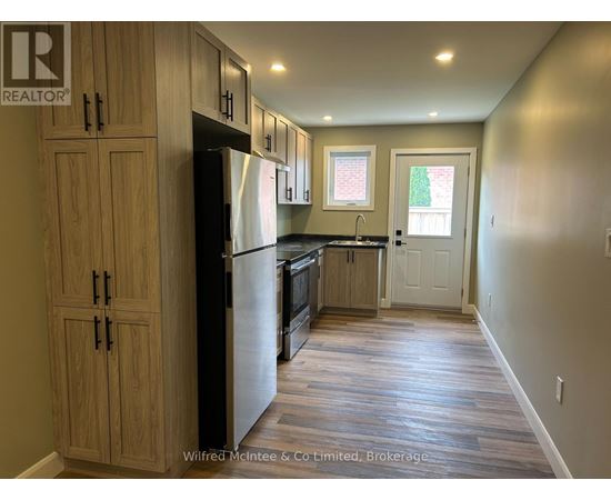 A kitchen with wooden cabinets and a black refrigerator.