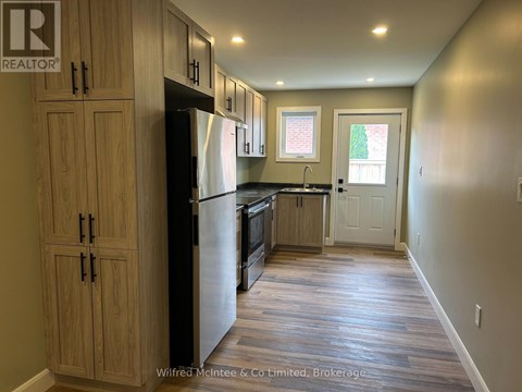 A kitchen with wooden cabinets and a black refrigerator.