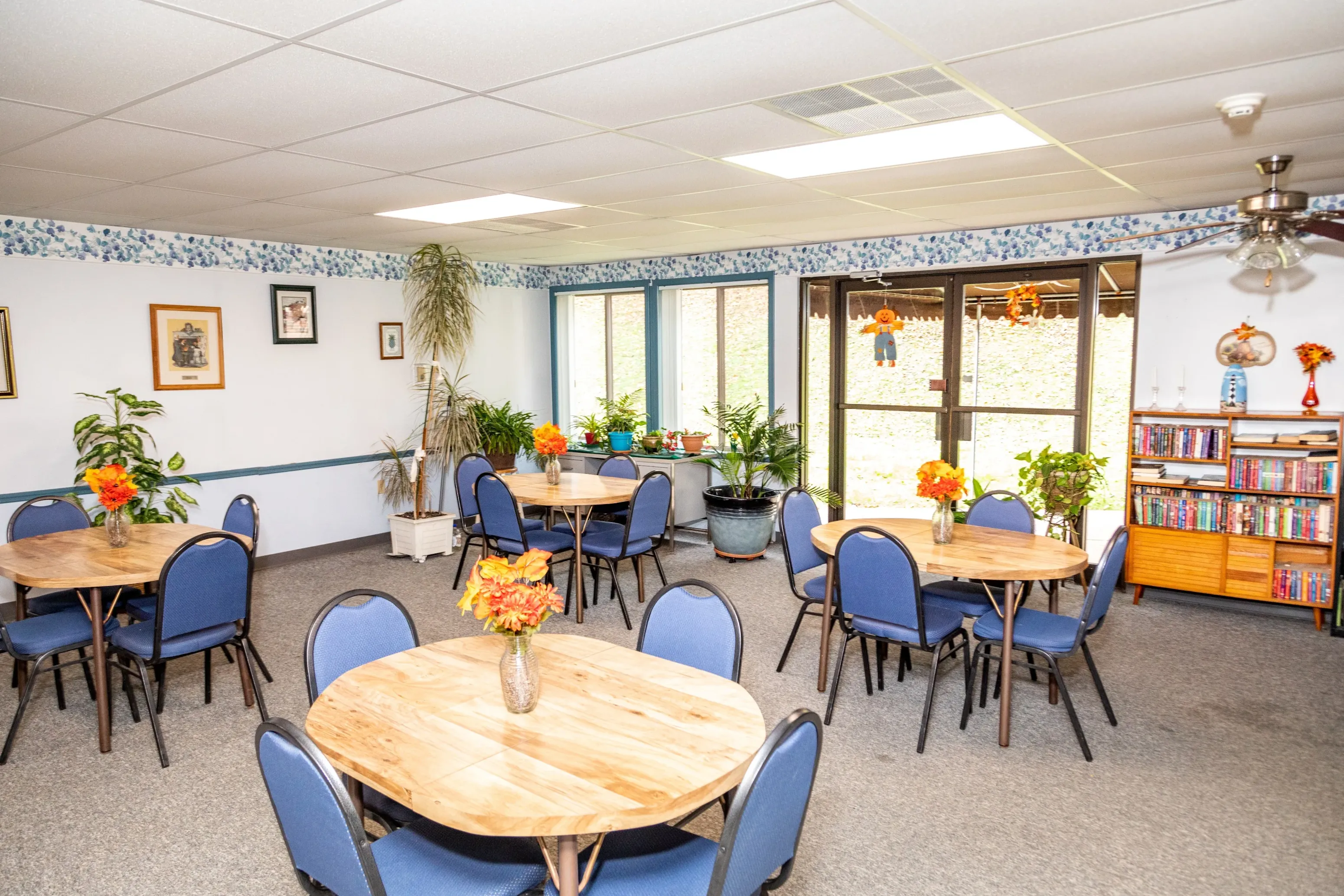 A room with tables and chairs and a ceiling fan.