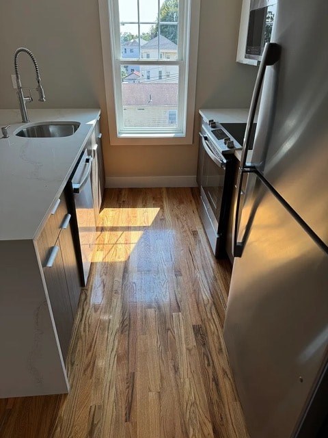 A kitchen with a refrigerator, sink, and window.
