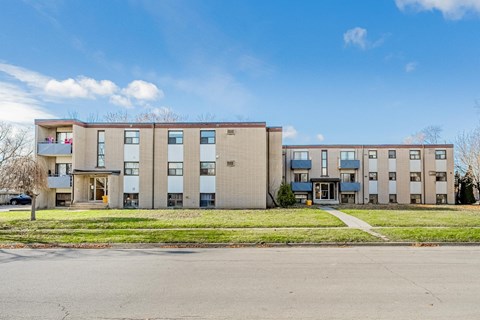 Apartment building with a blue sky and clouds in the background.