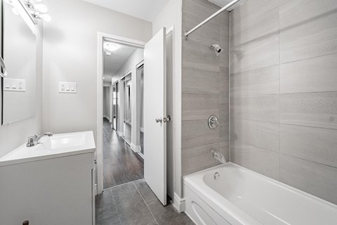 A bathroom with a white sink, bathtub, and tiled walls.