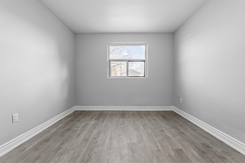 A room with a window and wooden flooring.
