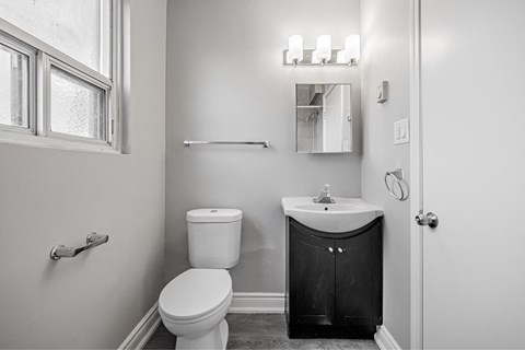 A bathroom with a toilet, sink, and mirror.