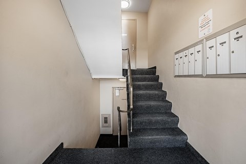 A staircase with a metal railing and a black carpeted floor.