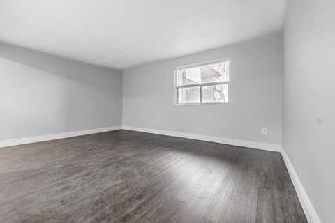 A room with a window and wooden flooring.