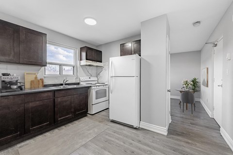 A kitchen with a white refrigerator and brown cabinets.