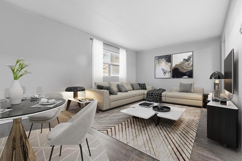 A modern living room with a glass table, a white sofa, and a TV on the wall.