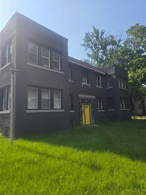 A black building with a yellow door and windows.