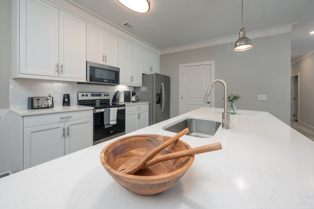 A kitchen with white cabinets and a wooden bowl on the counter.