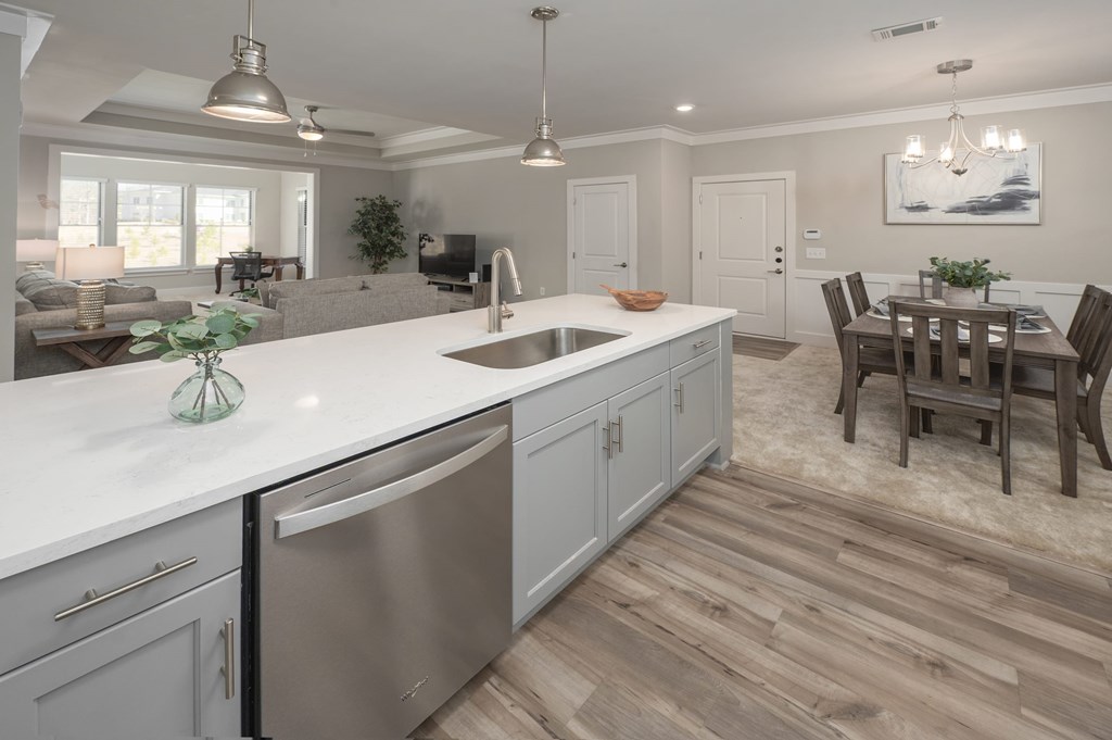 A modern kitchen with a wooden floor and white countertops.