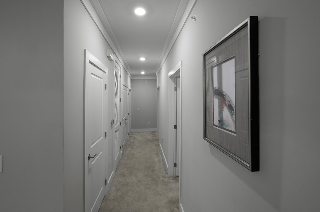 A hallway with white doors and a framed picture on the wall.