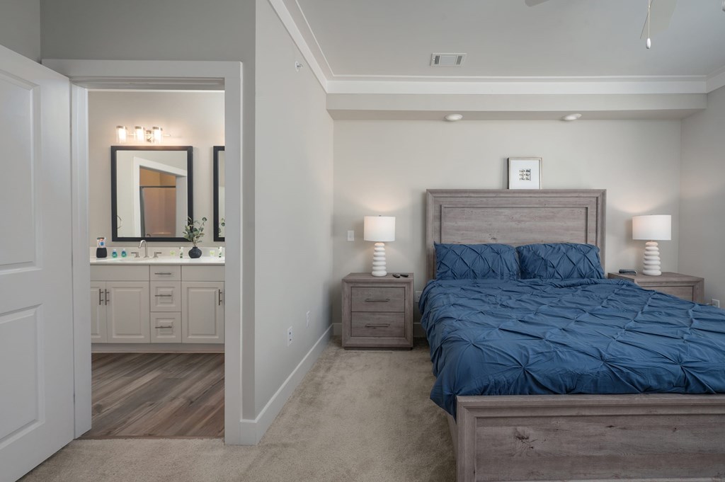 A bedroom with a bed, nightstands, and a mirrored cabinet.