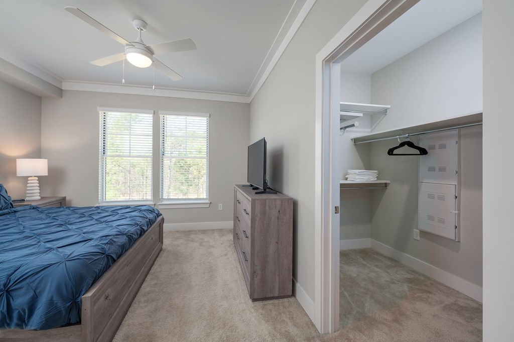A bedroom with a bed, dresser, and a television.