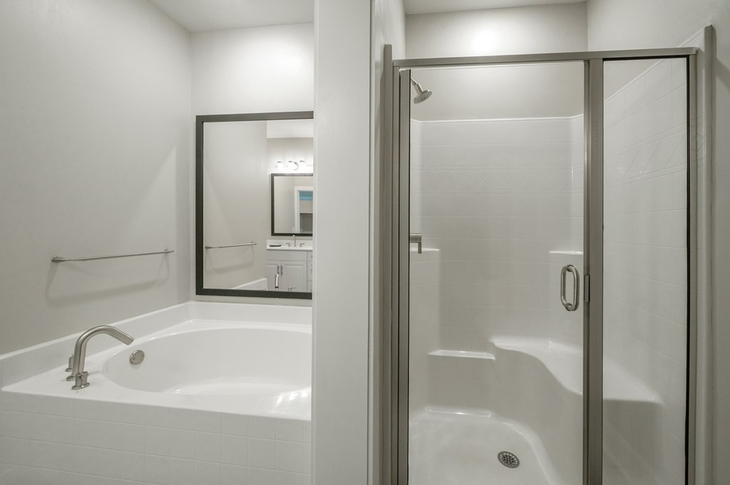 A white bathroom with a glass shower door and a white tub.