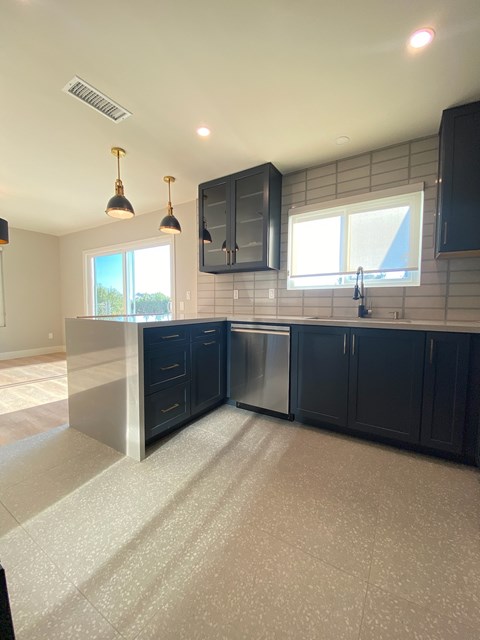 A kitchen with dark blue cabinets and a tiled backsplash.