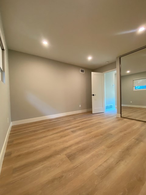 A room with wooden flooring and a mirror on the wall.