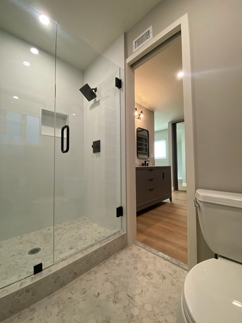 A bathroom with a glass shower stall and a toilet.