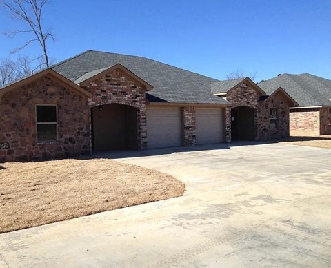A house with a grey roof and stone walls has three garages.
