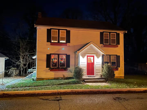 A house with a red door is lit up at night.