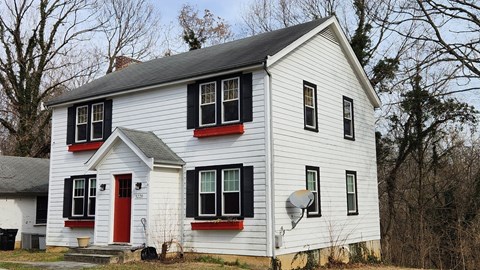 A white house with a red door and black shutters.