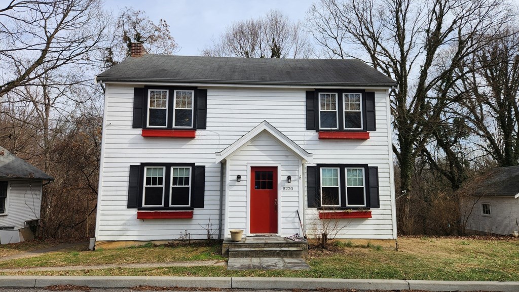 A white house with a red door and black shutters.