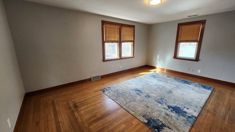 A room with wooden floors and a rug in the middle.