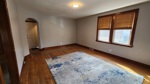 A room with a blue rug and wooden floors.