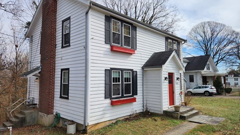 A white house with a red door and black shutters.